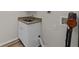 Laundry room with utility sink, white cabinets, and wood-look floors at 5280 Oak Hill Ter, Cumming, GA 30040