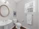 Bright powder room featuring a pedestal sink, oval mirror, and window with blinds at 5280 Oak Hill Ter, Cumming, GA 30040