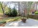 A peaceful fenced backyard with green grass, mature trees, and a fire pit on the patio at 1855 Keswick Place Dr, Lawrenceville, GA 30043