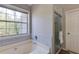 Bright bathroom including window over tub with glass enclosed shower at 1855 Keswick Place Dr, Lawrenceville, GA 30043