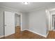 A bedroom with neutral colored paint, white trim, and hardwood flooring with light coming from an adjacent room at 5074 Park Ave, Forest Park, GA 30297