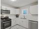 Updated kitchen with white cabinets, stainless steel appliances, and marble-patterned tile floor at 5074 Park Ave, Forest Park, GA 30297