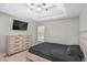 Cozy bedroom with neutral walls, carpet, TV, ceiling fan, dresser, and a comfortable black bed at 7847 Wrotham Cir, Atlanta, GA 30349