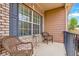 Inviting front porch featuring two wicker chairs, a small table, and a view of the surrounding landscape at 7847 Wrotham Cir, Atlanta, GA 30349