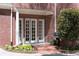Brick patio entrance with double french doors, white columns, and professionally landscaped flower bed at 1209 The By Ne Way, Atlanta, GA 30306