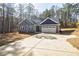 Inviting gray home with stone accents, long driveway, and a two-car garage nestled in a wooded area at 5328 Monticello Dr, Villa Rica, GA 30180