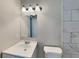 Bathroom featuring a white sink, toilet, light fixture and tile, plus a large mirror at 908 Kennesaw Dr, Forest Park, GA 30297