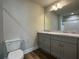Bright bathroom featuring wood-look flooring, gray double vanity with a light countertop, a toilet and a large mirror at 6420 Olmadison Pl, Atlanta, GA 30349