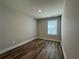 Empty room featuring wood-look flooring, a window with blinds and neutral paint at 6420 Olmadison Pl, Atlanta, GA 30349