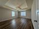 Primary bedroom features tray ceiling, fan, and wood-look floors at 6420 Olmadison Pl, Atlanta, GA 30349