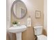 Powder room with pedestal sink, round decorative mirror, and modern fixtures at 5965 Ellington Cv, Cumming, GA 30040