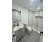 Renovated bathroom featuring a gray vanity, toilet, glass-enclosed shower with a shelf, and gray tile flooring at 4651 S Roberts Drive, Sugar Hill, GA 30518