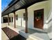 Inviting front entrance with a wooden door, white brick, and dark wood columns at 4651 S Roberts Drive, Sugar Hill, GA 30518