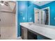 Bright blue bathroom featuring a sleek vanity, framed mirror, and an adjacent doorway at 508 Arbor Trl, Loganville, GA 30052