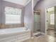 Bright bathroom with a soaking tub, tiled shower, and muted purple walls at 508 Arbor Trl, Loganville, GA 30052