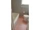 A compact bathroom with a tub, toilet, and gray tiled walls with unique pink hexagonal tile flooring at 2213 Sharon Way, Decatur, GA 30032