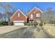 Charming two-story brick home featuring a manicured front lawn, attached garage, and symmetrical design elements at 1824 Kristen Ct, Suwanee, GA 30024