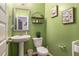 Charming half bathroom with green walls, pedestal sink, toilet, and decorative wall art at 5761 Sawgrass Cir, Lithonia, GA 30038