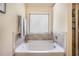 Relaxing bathroom features a soaking tub with decorative tile surround and a window for natural light at 5761 Sawgrass Cir, Lithonia, GA 30038