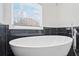 Freestanding tub with wall-mounted faucet surrounded by black marble tile at 300 Lakeside Dr, Covington, GA 30016