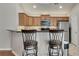 Well-lit kitchen featuring wooden cabinets, granite countertops, stainless steel appliances, and stylish barstool seating at 4927 Magnolia Cottage Way, Acworth, GA 30101