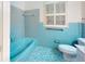 Aqua bathroom featuring blue tiled wall and floors, tub, toilet, and window with white shutters at 993 Castle Falls Dr. Ne Dr, Atlanta, GA 30329
