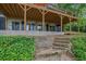 Covered basement patio featuring outdoor seating and access to the landscaped backyard, with stone steps leading up at 132 Lakeshore Dr, Roswell, GA 30075
