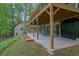 Covered basement patio with outdoor seating overlooking a lush backyard and the adjacent neighboring house at 132 Lakeshore Dr, Roswell, GA 30075
