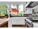 Modern kitchen features a stainless steel range, white cabinetry, farm sink, and picturesque windows offering beautiful outdoor views at 132 Lakeshore Dr, Roswell, GA 30075