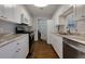 Galley kitchen features stainless steel appliances, granite countertops, white cabinetry and wood flooring at 207 Bridge Se Ln, Smyrna, GA 30082