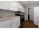 Galley kitchen features stainless steel appliances, granite countertops, white cabinetry and wood flooring at 207 Bridge Se Ln, Smyrna, GA 30082