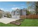 Side view of the home featuring a two-car garage, lush lawn and raised planting beds at 21 Enclave Walk, Powder Springs, GA 30127