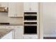 Modern kitchen featuring stainless steel double ovens, white cabinets, and granite countertops with tile backsplash at 308 Overture Ct, Smyrna, GA 30080