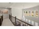 An upstairs hallway with a modern chandelier and natural light from the floor-to-ceiling living room windows at 11620 Crestview Ter, Johns Creek, GA 30024
