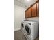 Laundry room equipped with modern washer and dryer, cabinets, and patterned rug on tile flooring at 11620 Crestview Ter, Johns Creek, GA 30024