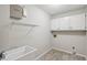 Tiled laundry room with a utility sink, shelving, and white cabinets provides ample space and storage solutions at 1431 Brandy Shoals Se Ct, Conyers, GA 30013