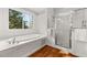 Bright bathroom featuring an elegant soaking tub, separate glass shower, and window with backyard views at 1904 Woodland Hills Nw Ave, Atlanta, GA 30318