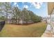 View of the expansive backyard enclosed by a black fence and lined with mature trees at 3365 Preservation Cir, Lilburn, GA 30047