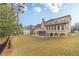 Large backyard with a spacious lawn and a multi-story home with a deck and sunroom at 3365 Preservation Cir, Lilburn, GA 30047