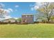 Large backyard with lush green grass, a wooden deck, and mature trees providing shade at 105 Oakfield Way, Douglasville, GA 30134