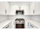 Close-up of a kitchen featuring white cabinets, stainless steel appliances, and bright quartz countertops at 1861 Dyer Cir, Atlanta, GA 30341
