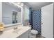 Well-lit bathroom with a commode, vanity with sink and mirror, and blue patterned shower curtain at 615 Upland Nw Trl, Conyers, GA 30012