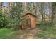 Small storage shed with a dark wood door in the wooded backyard at 615 Upland Nw Trl, Conyers, GA 30012