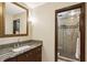 Bathroom with modern vanity, decorative mirror, and tiled shower with glass door at 240 W Spalding Dr, Sandy Springs, GA 30328