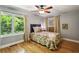 Bedroom featuring hardwood floors, large windows, and a cozy floral-patterned bed at 240 W Spalding Dr, Sandy Springs, GA 30328