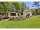 Well-manicured front lawn with a mid-century modern home, lush greenery, and tastefully landscaped flowerbeds at 240 W Spalding Dr, Sandy Springs, GA 30328