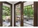 A view of the patio, through the french doors, that shows ample seating, and overlooks a verdant wooded back yard at 240 W Spalding Dr, Sandy Springs, GA 30328