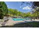Outdoor community pool with lounge chairs and a covered seating area surrounded by lush greenery and blue skies at 240 W Spalding Dr, Sandy Springs, GA 30328