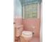 Close-up of vintage pink toilet and tile, showcasing a retro bathroom design with small window at 2992 Westminster Nw Cir, Atlanta, GA 30327