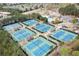 Aerial view of multiple well-maintained tennis courts with lighting and shade pavilions surrounded by lush trees at 3225 Suffolk Dr, Cumming, GA 30041